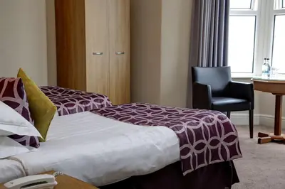 a hotel room with two beds and a chair at Best Western Lancaster Morecambe Lothersdale Hotel in Morecambe