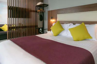 a bedroom with a large bed with two yellow pillows at Best Western Lancaster Morecambe Lothersdale Hotel in Morecambe