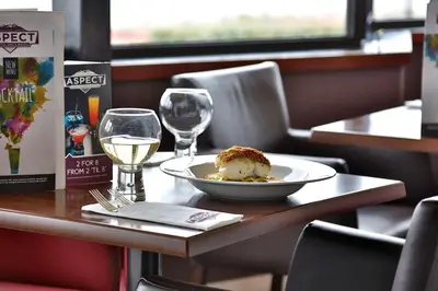 a table with a plate of food and two glasses of wine at Best Western Lancaster Morecambe Lothersdale Hotel in Morecambe