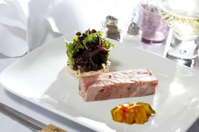 a white plate with a piece of meat and a salad at Best Western Lancaster Morecambe Lothersdale Hotel in Morecambe