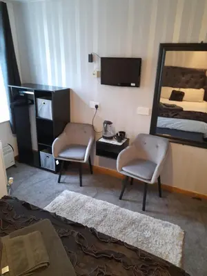 a bedroom with a bed and two chairs and a mirror at The Fame in Blackpool