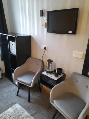 a living room with two chairs and a tv at The Fame in Blackpool