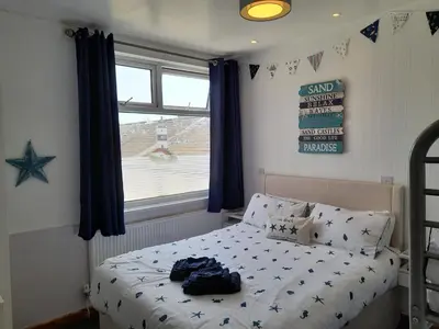 a bedroom with a bed with blue curtains and a window at The Fame in Blackpool