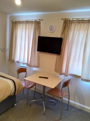 a room with a desk and a bed and a tv at Denny Guests House / Green Lane in Liverpool