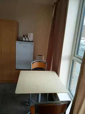 a table and chairs in a room with a refrigerator at Denny Guests House / Green Lane in Liverpool