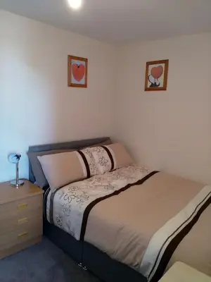 a small bedroom with a bed and a night stand at Denny Guests House / Green Lane in Liverpool