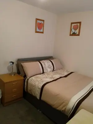 a bedroom with two beds and a night stand at Denny Guests House / Green Lane in Liverpool