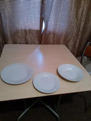 two white plates sitting on top of a wooden table at Denny Guests House / Green Lane in Liverpool