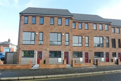 a brick building with red doors on a street at Denny Guests House / Green Lane in Liverpool