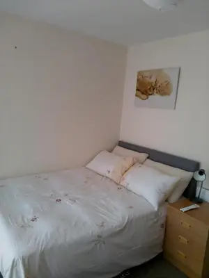 a small bedroom with a bed with white sheets at Denny Guests House / Green Lane in Liverpool