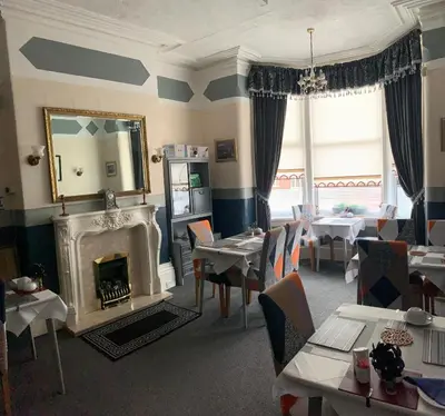 a dining room with a fireplace and tables and a mirror at Hornby Villa B&B Couples & Families Only- Quiet Central Location- Near To Winter Gardens in Blackpool