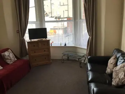 a living room with a couch and a tv and a window at Beach View Holiday Flats in Blackpool