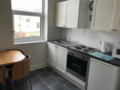 a kitchen with white cabinets and a stove top oven at Beach View Holiday Flats in Blackpool