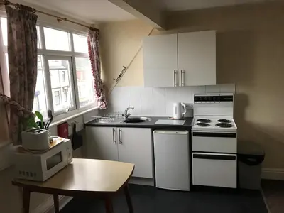 a small kitchen with white appliances and a table at Beach View Holiday Flats in Blackpool