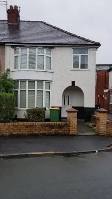 a white house with a brick fence in front of it at Central Location Preston 2 in Preston