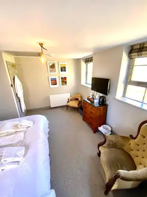 a bedroom with a bed and a chair and a tv at The Stables, Ulverston in Ulverston
