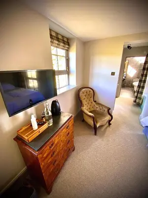 a bedroom with a dresser and a chair and a television at The Stables, Ulverston in Ulverston