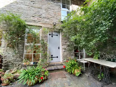 a stone house with a white door and a bench at The Stables, Ulverston in Ulverston