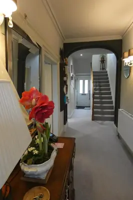 a hallway with a staircase and a vase with a flower at Kentwood Guest House in Arnside