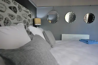 a bedroom with a bed with mirrors on the wall at Kentwood Guest House in Arnside