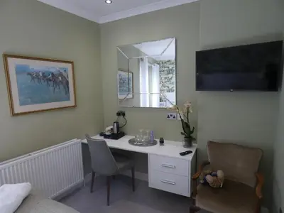 a bedroom with a desk with a mirror and a bed at Kentwood Guest House in Arnside