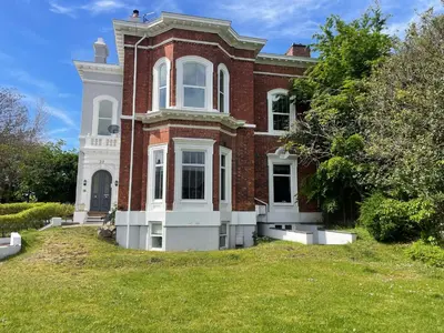 a large red brick house with a grass yard at Beach House - Penthouse 3 Bed Apartment in Southport