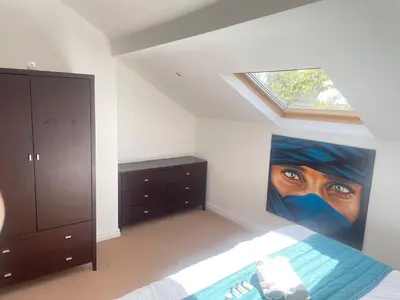 a bedroom with a painting of a face on the wall at Beach House - Penthouse 3 Bed Apartment in Southport