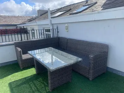 a patio with a glass table and two wicker chairs at Beach House - Penthouse 3 Bed Apartment in Southport