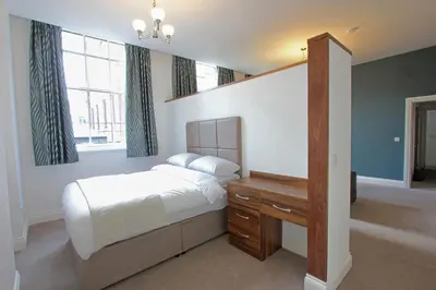 a bedroom with a bed and a desk and windows at The Castle Collection - 3 Union Court in Liverpool