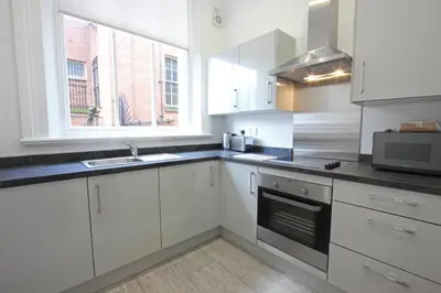 a kitchen with white cabinets and a sink and a window at The Castle Collection - 3 Union Court in Liverpool