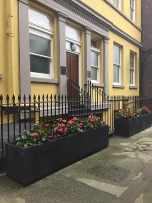 a black fence with flowers in front of a building at The Castle Collection - 3 Union Court in Liverpool
