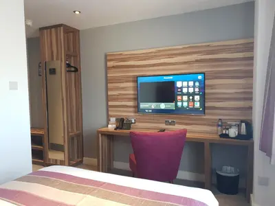a room with a desk with a television on a wall at Escape Hotel in Barrow in Furness