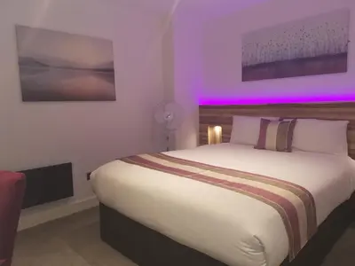 a bedroom with a large bed with purple lighting at Escape Hotel in Barrow in Furness