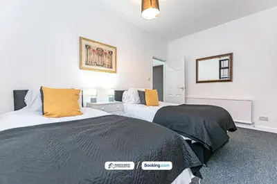 two beds in a room with white walls and yellow pillows at Wigan Work-Ready 3BR House Sleeps 6 Guests in Wigan