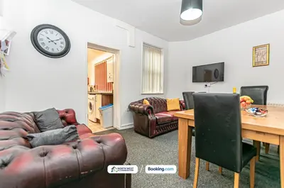 a living room with a couch and a table and a clock at Wigan Work-Ready 3BR House Sleeps 6 Guests in Wigan