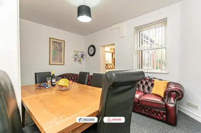 a dining room with a table and a leather couch at Wigan Work-Ready 3BR House Sleeps 6 Guests in Wigan