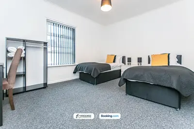 a bedroom with two beds and a table and a chair at Wigan Work-Ready 3BR House Sleeps 6 Guests in Wigan
