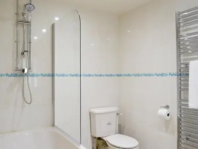 a white bathroom with a shower and a toilet at Woodpecker Cottage - Ukc3412 in Bolton by Bowland