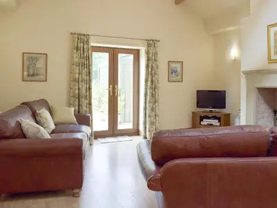 a living room with two leather couches and a television at Woodpecker Cottage - Ukc3412 in Bolton by Bowland