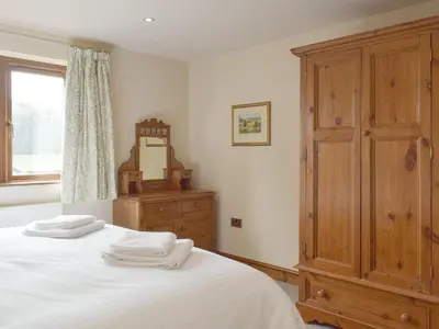 a bedroom with a bed with white sheets and a wooden cabinet at Woodpecker Cottage - Ukc3412 in Bolton by Bowland
