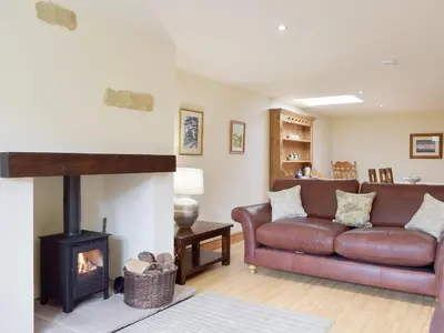 a living room with a leather couch and a wood stove at The Old Dairy - Ukc3413 in Bolton by Bowland