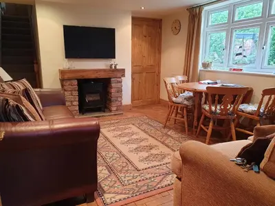 a living room with a fireplace and a table at The Coach House Holiday Cottage, Southport in Southport