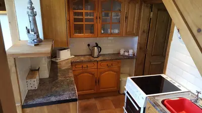 a small kitchen with wooden cabinets and a stove at The Coach House Holiday Cottage, Southport in Southport