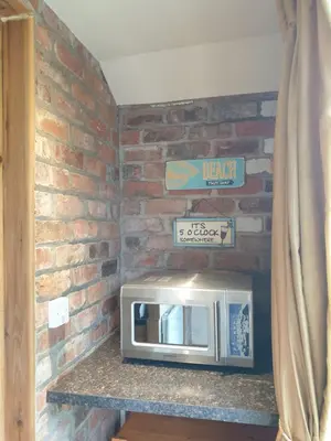 a microwave on a counter with a brick wall at The Coach House Holiday Cottage, Southport in Southport