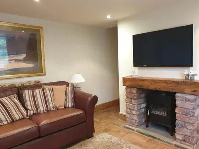 a living room with a couch and a fireplace with a flat screen tv at The Coach House Holiday Cottage, Southport in Southport
