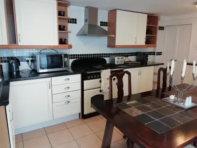 a kitchen with white cabinets and a table and a microwave at Brown Cow Cottage in Dalton in Furness