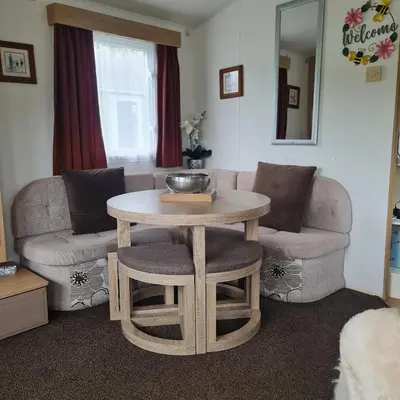 a living room with a table and a couch at Carmels Caravan Borwick Lakes in Carnforth