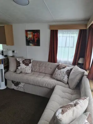 a living room with a sectional couch with pillows at Carmels Caravan Borwick Lakes in Carnforth