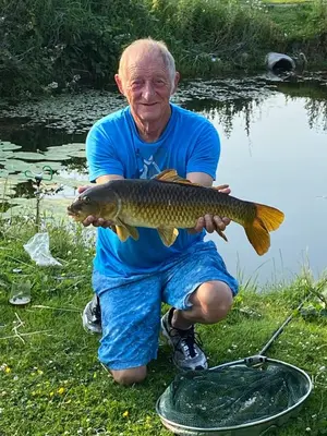 a man holding a fish in front of a pond at Carmels Caravan Borwick Lakes in Carnforth