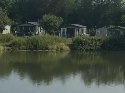 a group of houses next to a body of water at Carmels Caravan Borwick Lakes in Carnforth